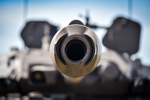 Detail shot with the muzzle brake of a modern tank. Blurry background.