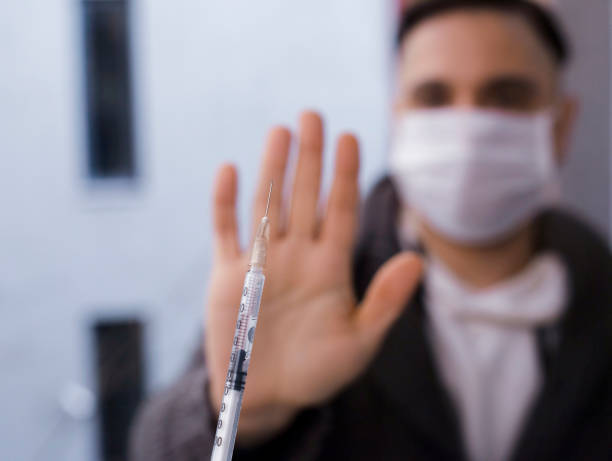 istock Holding up hand to stop a COVID-19 vaccination syringe 1447720869