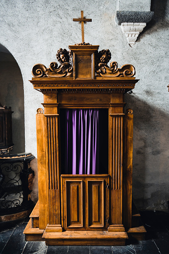 Typical old wooden confession booth at a church, with blue curtains.