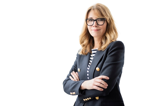 Mature female with arms crossed. Confident businesswoman is against isolated white background. Attractive woman wearing eyewear and blazer.