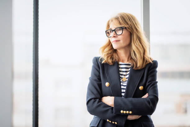 istock Executive business woman looking thoughtfully while standing with arms crossed at the office 1447731577