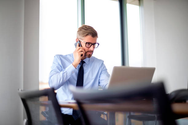 istock Professional businessman using mobile phone and laptop while working in a modern office 1447731614