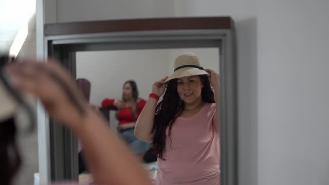 Woman trying on a hat in front of a mirror at home