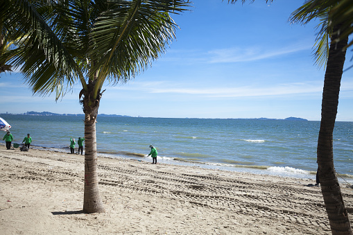 Thai cleaner staff is cleaning up Bang Saen beach in Chonburi at bright sunny day. View from promenade