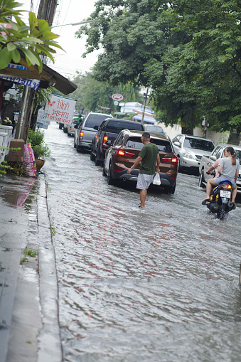 Traffic jam in flooded street in Bangkok Nawamin. Street is leading to main road and intersection Nawamin Road. A man is walking in water behind cars