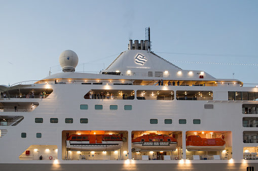 Zadar, Croatia - 30 October 2022: Side view of the cruise ship with passengers aboard and lights on during the evening, Silversea Cruises