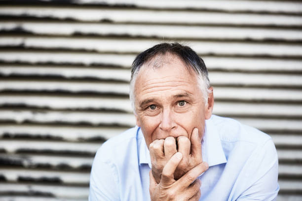 un hombre guapo ansioso y preocupado se muerde las uñas nerviosamente, con espacio de copia en la puerta enrollable detrás de él - nail biting guilt men anxiety fotografías e imágenes de stock