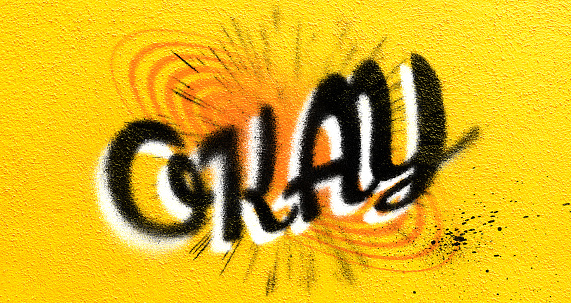 Color image of a wall that has graffiti designs on it.