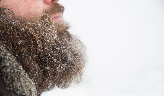 Bearded man in snowy weather on the street in the snow. Snow on the beard