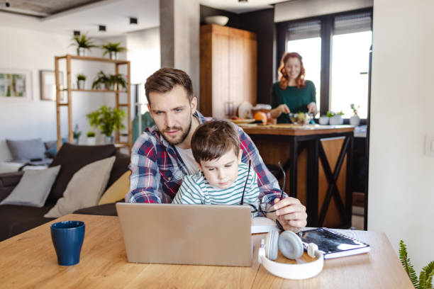 istock Father works on a laptop and holds his son on his lap 1447753721