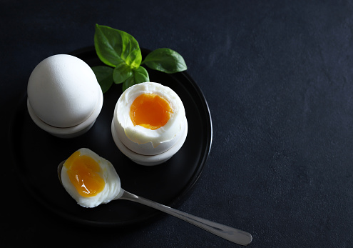 Soft boiled egg isolated on dark background. Directly above. Copy space.