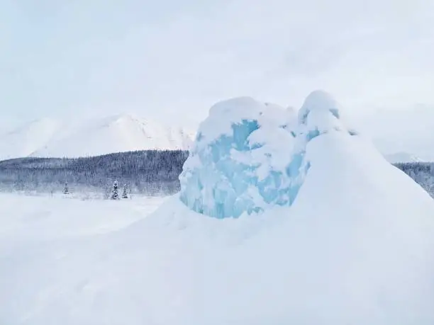 Frozen fountain in shape of blue ice hill in Khibiny mountains. Winter natural phenomenon. Kirovsk, Kola Peninsula, Murmansk region.