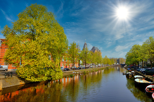 Beautiful river canal with boats and green trees in Amsterdam, Holland Netherlands.