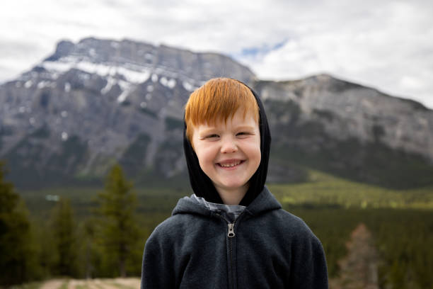 Young 6 years old redhead boy smiling and looking at the camera while hiking the Hoodoos Trails in Banff, Alberta, Canada.