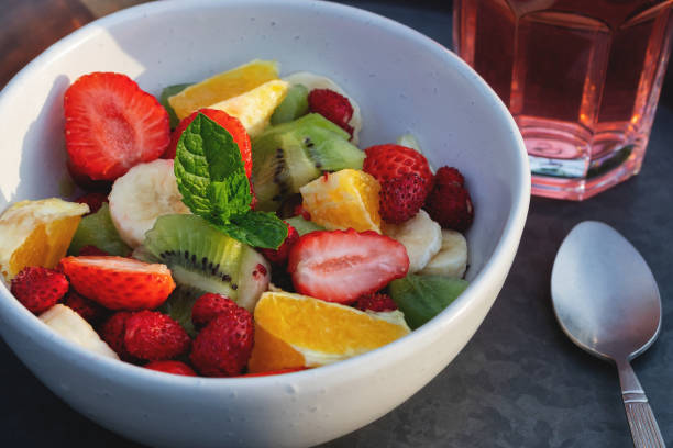 istock Fruit salad in a white bowl on a tray with a drink and a spoon 1447765288