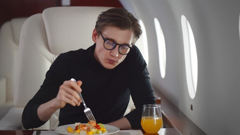 Handsome young businessman eating salad in private jet