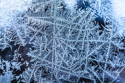 A frame of a frosty pattern of ice crystals on a black background. A frame with an abstract ice structure allows you to apply or add a frost effect. Frost on the glass, freezing effect