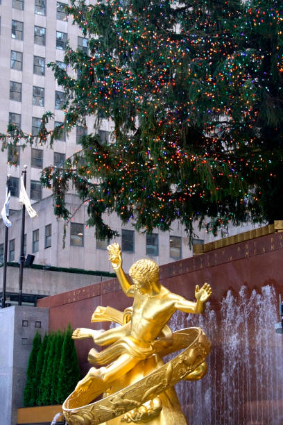 christmas lights on the rockefeller center tree above the prometheus statue New York, NY, USA-December 6, 2022: Holiday tradition-Rockefeller Center renovated buildings allow views around the rink at the rink level of this complex. Pictured here- the Rockefeller Christmas tree above the Prometheus statue rockefeller ice rink stock pictures, royalty-free photos & images
