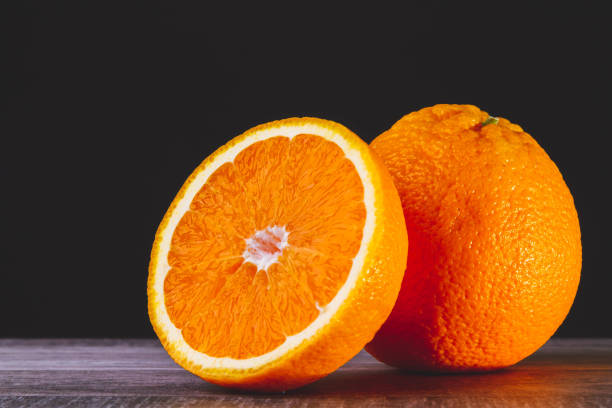 istock Half an orange. Two halves of fruit on a wooden table. Copyspace. 1447771851