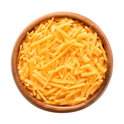 Shredded cheddar cheese, in a wooden bowl. Grated natural cheese, piquant, colored orange with annatto, a natural food coloring. Rolled in starch to avoid sticking. Used for pizza and pasta dishes.