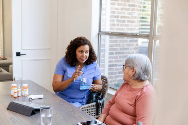 istock Visiting nurse holds pill box while reviewing dosage with senior 1447777086