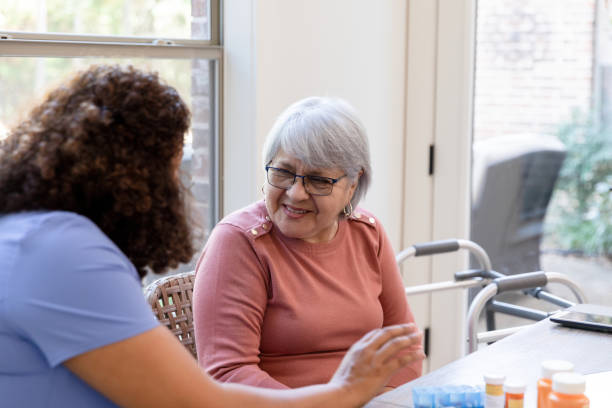 istock Senior woman smiles while trying to understand visiting nurse 1447777094