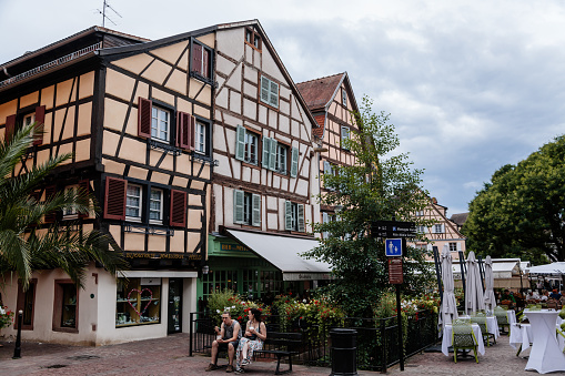 Colmar, Alsace, France, 4 July 2022: town capital of Alsatian wine, narrow picturesque street with medieval colorful houses, Timber framing or post-and-beam construction, romantic city at summer day