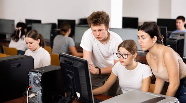 istock Concentrated boy helping   young female students   working with pc in computer class 1447780758
