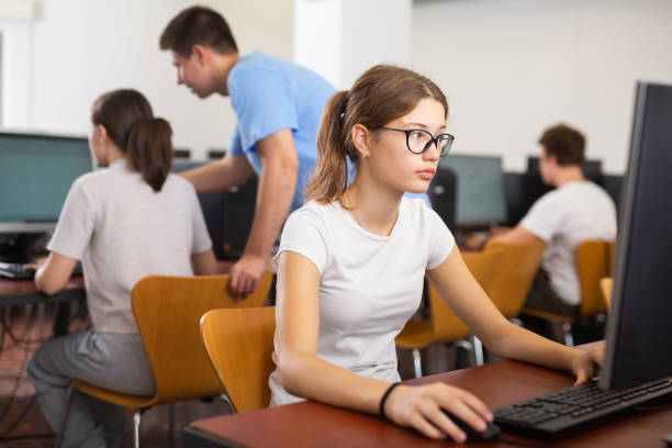 istock Interested young female student with glasses working on computer in library, looking for necessary information on Internet 1447780822