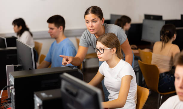 istock Clever female teenager helping to the female classmate while she is learning computer science in the class 1447781051