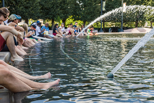 Washington, DC USA - July 19, 2019: People dipping their feet in the water fountain at the National Gallery of Art Sculpture Garden on the National Mall in the summer