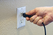 Man's hand plugging power cord into power