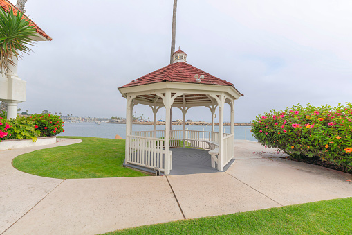 Gazebo outside a building on the seaside at Oceanside, California. Garden of a building with lawn and concrete pathway and deck against the sea at the background.