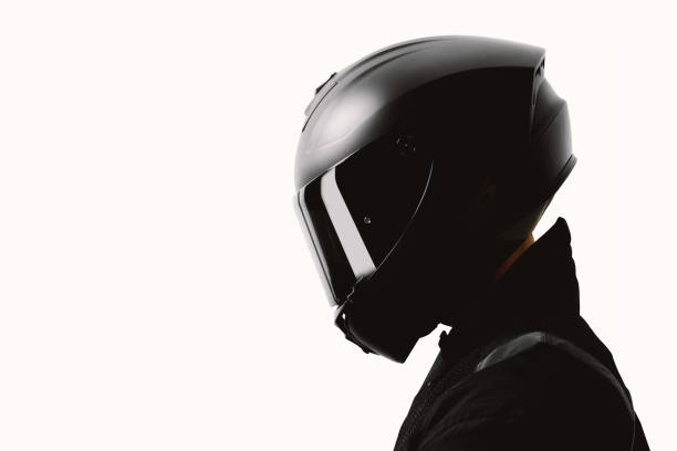 porträt eines motorradfahrers, der mit einem schwarzen helm auf weißem hintergrund posiert. - sports helmet stock-fotos und bilder