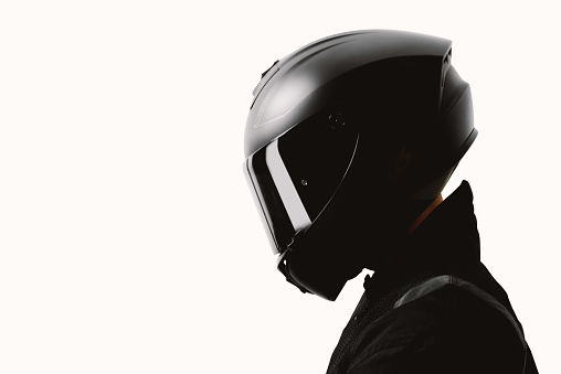 Portrait of a motorcycle rider posing with a black helmet on a white background.