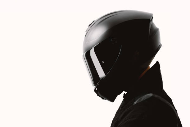 Portrait of a motorcycle rider posing with a black helmet on a white background. stock photo