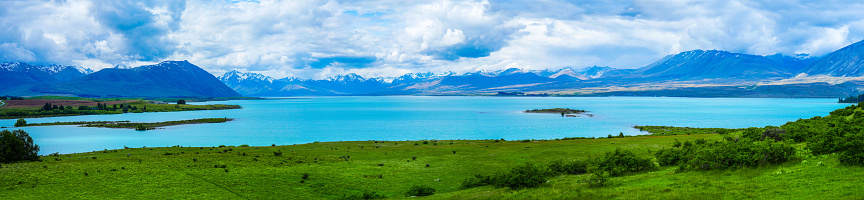 Expansive panoramic view of the bright blue glacial waters of Lake Tekapo in the South Island of New Zealand