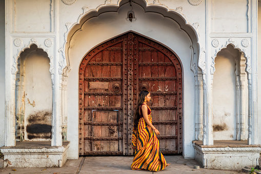 Young Indian woman, wearing sari, posing posing on streets of Jaipur, Rajasthan.