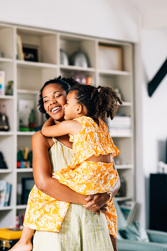 A pretty African-American child embracing her loving nanny while they are having fun at home.