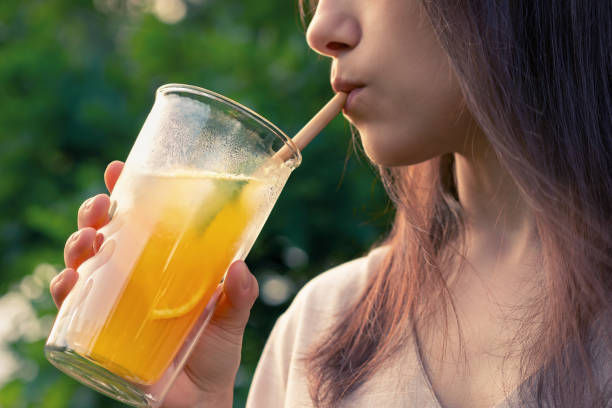 新鮮なオレンジ色の夏のカクテル、接写、選択フォーカスでグラスから飲む女の子 - close up women horizontal citrus fruit ストックフォトと画像