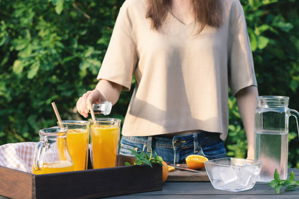 istock Girl cooking summer orange cocktail with mint and ice cubes outdoors, selective focus 1447807595