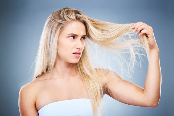 istock Upset, angry and annoyed woman with hair problem or style issue on a grey studio background. Damage, bad and expression of female unhappy with blonde hair loss for advertisement on a backdrop 1447810925