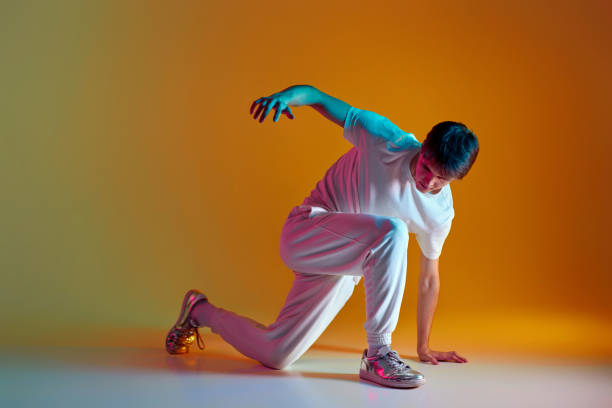 istock man dancing on yellow background. Neon lighting 1447813725