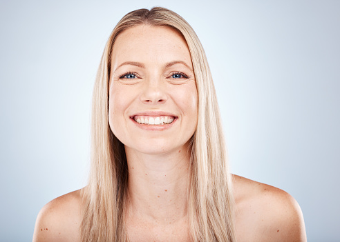 Hair care, cosmetics and portrait of a woman with a smile against a grey studio background. Skincare, wellness and face of a happy model with straight hair from the hairdresser with shine and clean