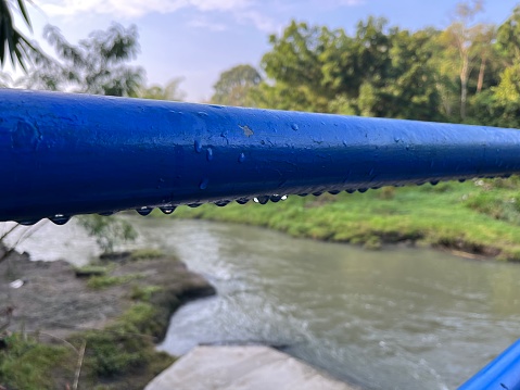 Blue steel railing with water drops and wet in the park.