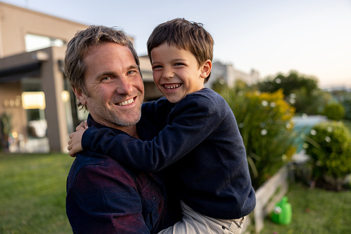 Portrait of a happy Latin American father and son smiling outdoors while looking at the camera