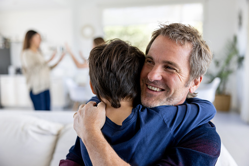 Portrait of a happy father hugging his son at home and smiling - family lifestyle concepts