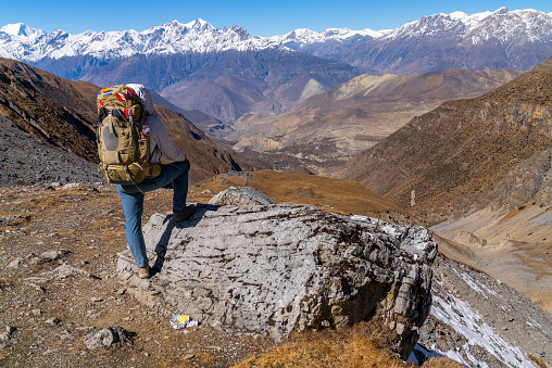 Trekker looking at view of himalayan mountains on the Annapurna Circuit Trek in the fall, Nepal