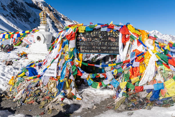 cartel y banderas de oración en el paso thorang la. escena en el área de conservación del annapurna, nepal. - muktinath fotografías e imágenes de stock