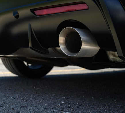 Close up of an exhaust pipe of a car, environmental pollution. Sunlight.